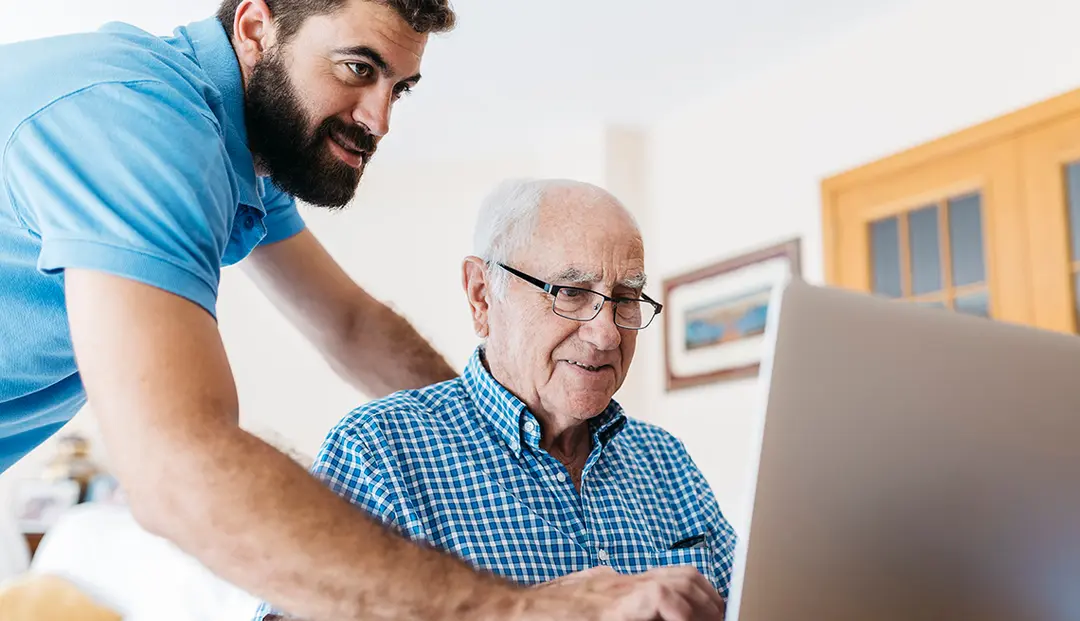 A Kawartha Tech Care technician helping a senior man with his laptop